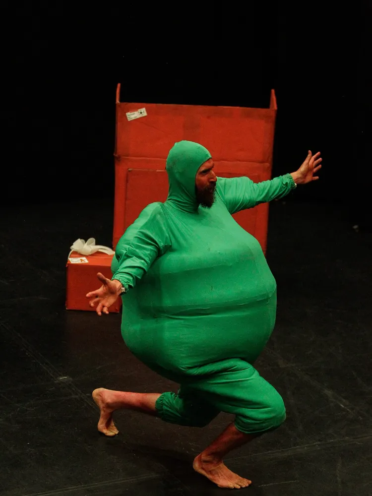 Daniel Orrantia de cuerpo entero con el traje verde, corriendo en el escenario